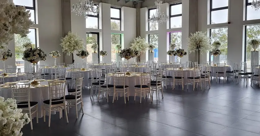 Runde, weiß eingedeckte Tafeln mit Blumenschmuck im Eventsaal