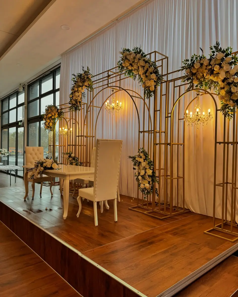 Bühne mit goldenen Bögen, Kronleuchtern und weißen Blumen für eine Verlobung